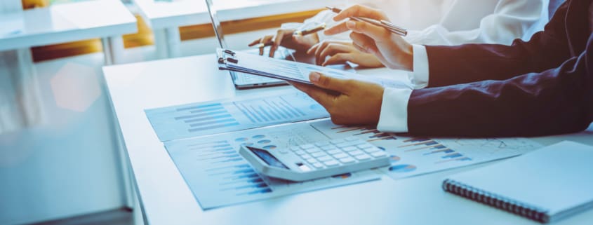 Close-up of two businesswomen calculating financial statements at a desk.