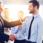 Two businessmen smiling while shaking hands